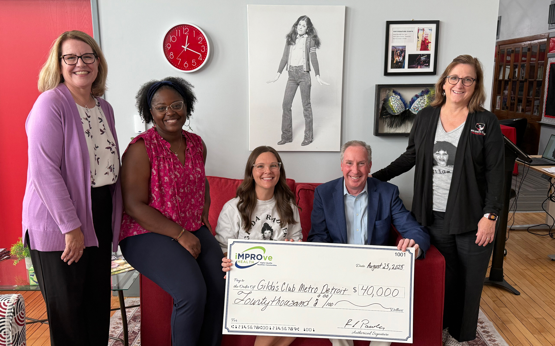 Photo of five individuals. Two are presenting a check to three other.